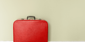 red suit case alone by wall