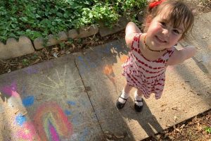 young girl displays sidewalk chalk art
