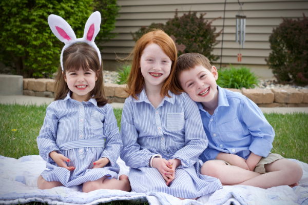 a pic of three smiling children in Easter outfits