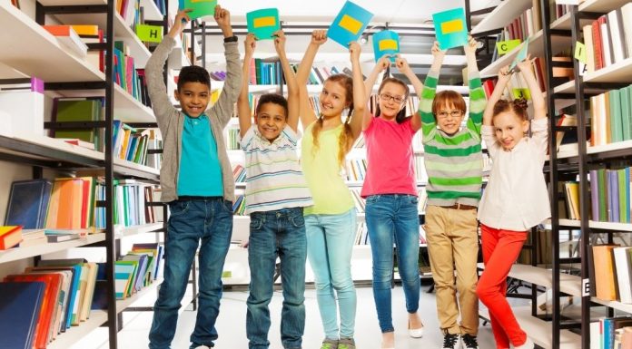 diverse group of kids in a library holding books