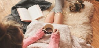 woman drinking hot cocoa, journaling, covered with a blanket