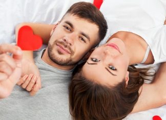 couple laying together holding hearts
