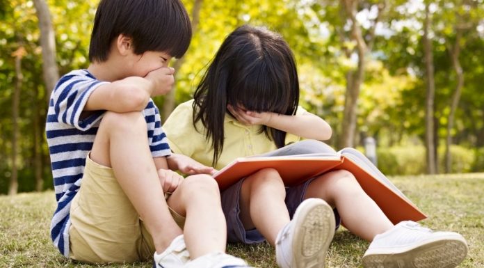 two asian children reading a book together