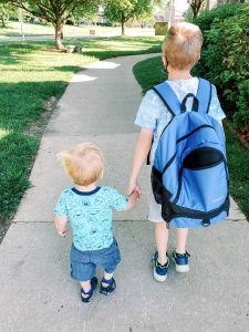 two little boys holding hands while walking