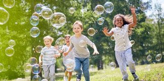 group of kids running through bubbles