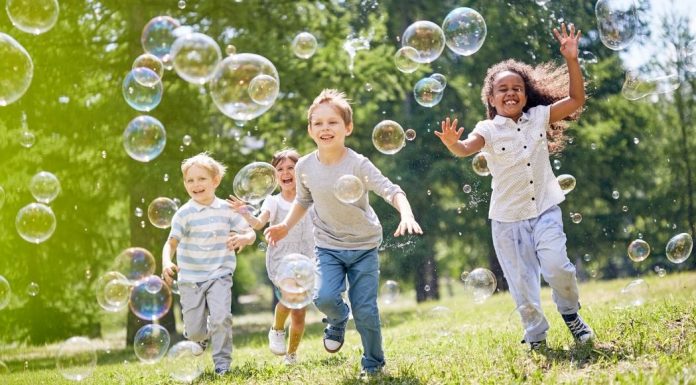 group of kids running through bubbles