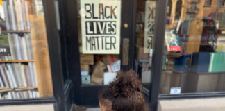 little girl walking by a Black Lives Matter poster