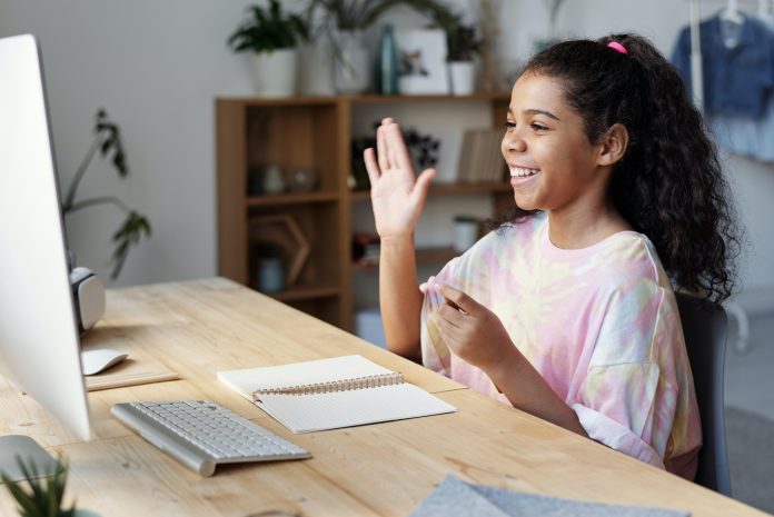 girl raising hand while looking at computer