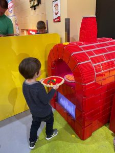 child making his own lego pizza in a lego brick oven