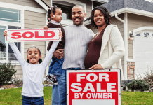 family with sold sign outside new home