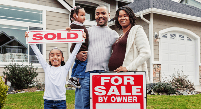 family with sold sign outside new home