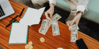 hands holding dollar bills and budget sheet