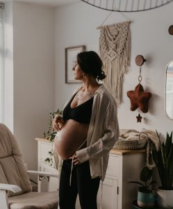 pregnant woman anxiously stares out the window in a baby nursery