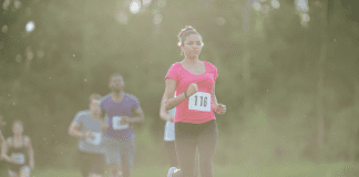 Young Black woman in pink shirt running race with a race bib on No. 118