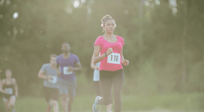 Young Black woman in pink shirt running race with a race bib on No. 118