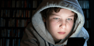 teen boy looking at phone in the dark