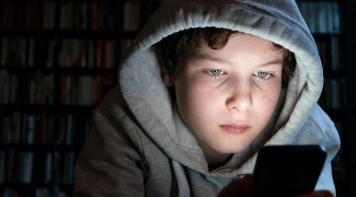 teen boy looking at phone in the dark