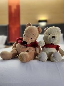 Stuffed Pooh Bears sitting on hotel bed